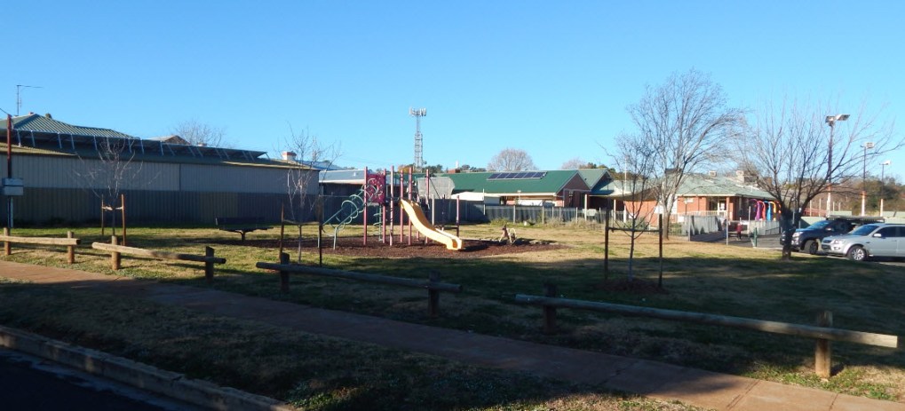 Photograph of AE Fox Park, with photographer on Armstrong Street. The playground equipment is a popular spot for young children and their parents, with Parkes Early Childhood Centre in the background. Photograph by Dan Fredericks (Parkes Shire Library) taken on July 21st, 2017