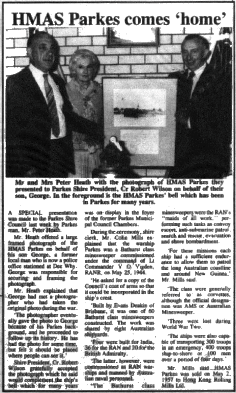 A framed photograph of HMAS Parkes is presented to Shire President Robert Wilson by Mr and Mrs Peter Heath. They are posing around the bell of HMAS Parkes, which today resides in Parkes Library. Source: Parkes Champion Post Monday, May 21, 1990 page 1
